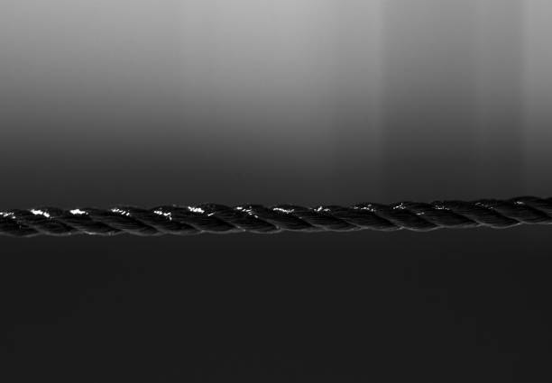 Black nylon rope in horizontal direction. Isolated on blurred black background. Close-up. Copy space.