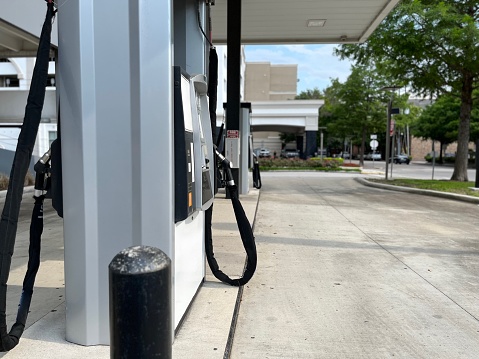 An alternative energy fueling station that could dispense natural gas or hydrogen is ready to receive vehicles.  In view are 2 pump set with 2 hoses each. The polished silver handler nozzles are a telltale sign of the alternative energy hose. Space to the right is ideal for copy.