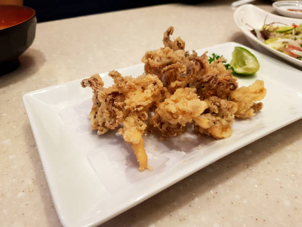 istock Deep fried squid with sliced lime or lemon in white dish on table at Japanese restaurant. 1496027419