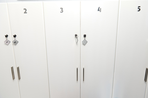 White numbered lockers in the corridor of the hallway or waiting room of a medical clinic, outpatient hospital, beauty parlor or spa salon in a minimalist stylish design. Copy advertising space