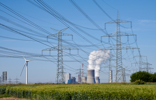 Brown-coal burning power plant with pollution and a group of electricity pylons.