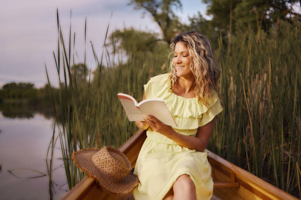 istock Happy woman enjoying in book during spring day in a canoe. 1496031504