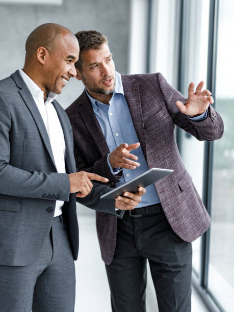 istock Happy male entrepreneurs working on digital tablet at corporate office. 1496032605