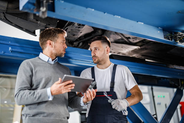 istock Auto mechanic and his manager talking while using touchpad in a repair shop. 1496032615