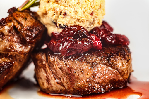A healthy meal of beef medallions with a side of dried tomatoes served on a plate.