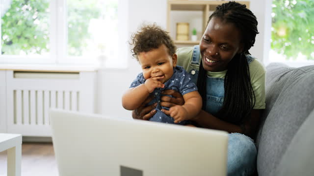 Mother and baby boy Black ethnicity having a video call via laptop