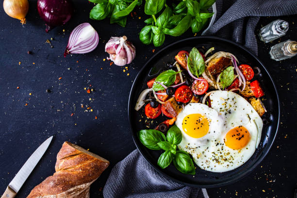 istock Continental breakfast -  sunny side up eggs white spinach, cherry tomatoes and olives on wooden table 1496037079