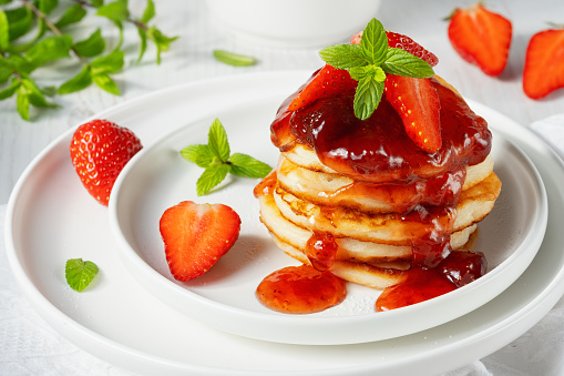 Mini pancakes with strawberry jam and strawberries.