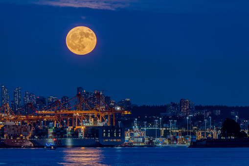 full moon rising above Vancouver Harbour at blue hour, BC, Canada