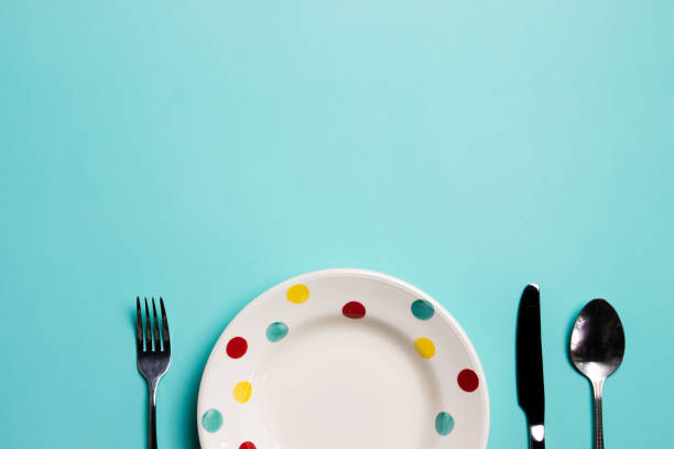 istock A colorful plate with fork and spoon on green background with copy space. 1496041661