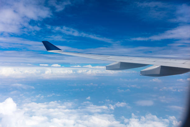 istock Airplane wing in flight and blue sky with white clouds 1496045059