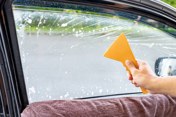 istock Using squeegee blade cleaning old car window film tint 1496045507