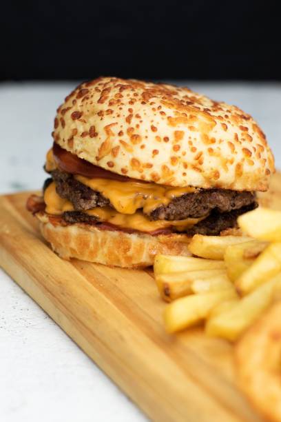 istock Delicious cheeseburger and fries meal displayed on a cutting board. 1496047169