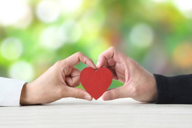 istock Couple's hand holding heart object together on light green background 1496047994