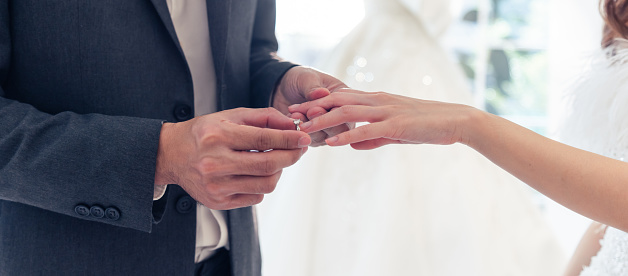 Close up of young man make surprise proposal of marriage to girlfriend. Attractive romantic male proposing to beautiful happy woman, with wedding ring enjoying surprise engagement in kitchen at home.