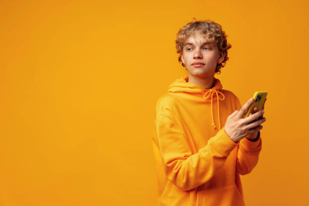 istock Happy caucasian young man using smartphone against yellow background 1496049699