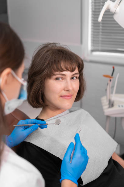 smiling girl in dentist's chair looks at her doctor with confidence, and then turns her gaze directly into camera and smiles,close-up.dental treatment by professional dentist in modern clinic.vertical - medical exam dental hygiene caucasian mask imagens e fotografias de stock