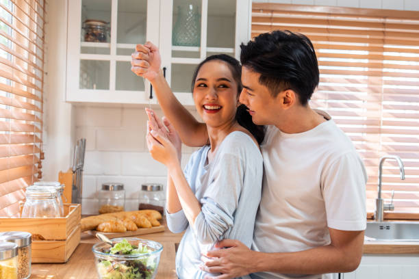 istock Asian romantic man making surprise girlfriend with necklace in kitchen. Attractive romantic new marriage couple male and female spend time celebrate anniversary and valentine's day together in house. 1496051607