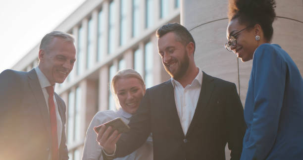 istock Diverse colleagues watching content on smartphone and laughing outdoors 1496053034