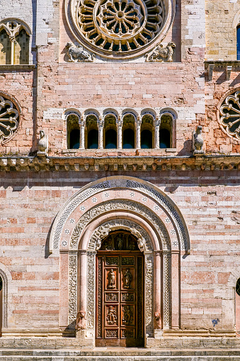 The beautiful side facade of the Cattedrale di San Feliciano (Cathedral of St Felician) in the medieval heart of Foligno, in Umbria. The Cathedral, or Duomo di Foligno, was built in Romanesque and Gothic style in the period 1133–1201 and dedicated to Felician who died in Foligno in 251 AD. Founded since pre-Roman times by the Umbrian people, Foligno was dominated by the Lombards and later by the Duchy of Spoleto. In the Middle Ages this city strategically placed between Spoleto and Perugia was an important trading center along the ancient Via Flaminia. The Umbria region, considered the green lung of Italy for its wooded mountains, is characterized by a perfect integration between nature and the presence of man, in a context of environmental sustainability and healthy life. In addition to its immense artistic and historical heritage, Umbria is famous for its food and wine production and for the high quality of the olive oil produced in these lands. Image in high definition quality.
