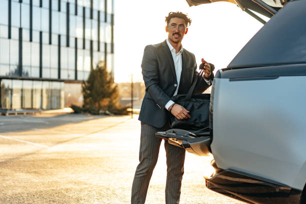 istock Successful businessman taking luggage from the car trunk 1496057477