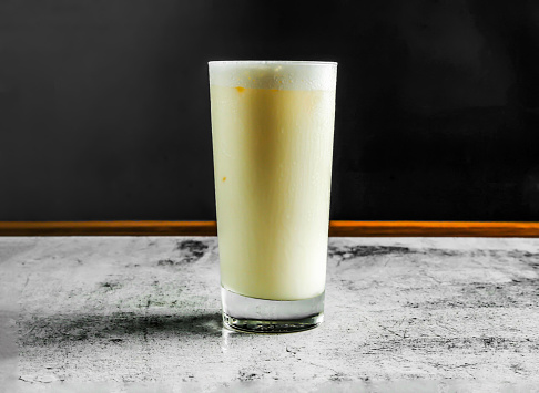 sweet lassi with yogurt, sugar, water and ice served in glass side view on grey background drink