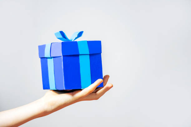 istock Cardboard blue gift box in hand on white wall background isolated 1496057834