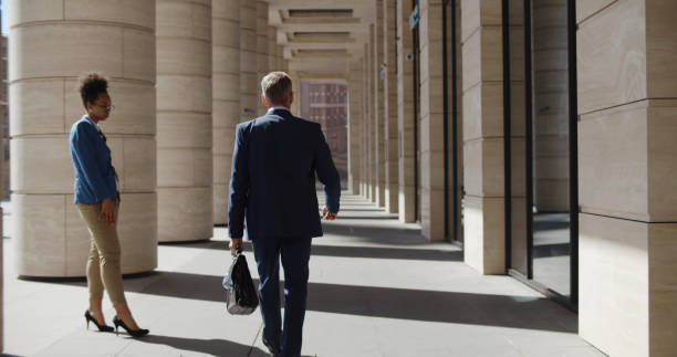 istock Back view of confident executive with briefcase walking outdoors downtown 1496058576