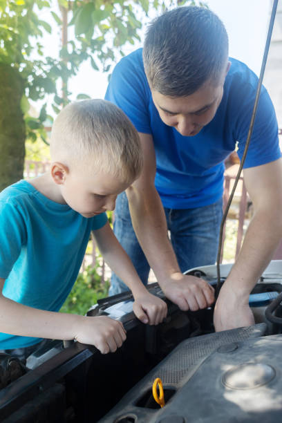 Shock due to irreparable damage. Timing belt break. Man and son near hood of car is looking for a malfunction due to which the engine does not work. Driver is holding a broken front belt in his hands. rotura de la correa de distribución. el hombre y el hijo cerca del capó del automóvil están buscando un mal funcionamiento debido a que el motor no funciona. el conductor sostiene un cinturón delantero roto en sus manos. choque debido a daños irrepar