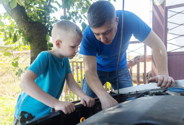 Shock due to irreparable damage. Timing belt break. Man and son near hood of car is looking for a malfunction due to which the engine does not work. Driver is holding a broken front belt in his hands. rotura de la correa de distribución. el hombre y el hijo cerca del capó del automóvil están buscando un mal funcionamiento debido a que el motor no funciona. el conductor sostiene un cinturón delantero roto en sus manos. choque debido a daños irrepar