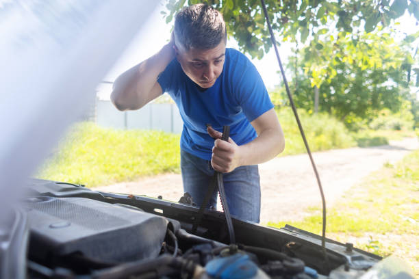 Shock due to irreparable damage. Timing belt break. Man near hood of car is looking for a malfunction due to which the engine does not work. Driver is holding a broken front belt in his hands. rotura de la correa de distribución. el hombre cerca del capó del automóvil está buscando un mal funcionamiento debido a que el motor no funciona. el conductor sostiene un cinturón delantero roto en sus manos. choque debido a daños irreparables.