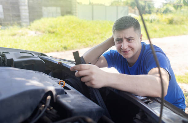 Shock due to irreparable damage. Timing belt break. Man near hood of car is looking for a malfunction due to which the engine does not work. Driver is holding a broken front belt in his hands. rotura de la correa de distribución. el hombre cerca del capó del automóvil está buscando un mal funcionamiento debido a que el motor no funciona. el conductor sostiene un cinturón delantero roto en sus manos. choque debido a daños irreparables.