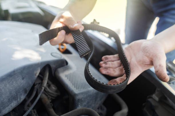 Shock due to irreparable damage. Timing belt break. Man near hood of car is looking for a malfunction due to which the engine does not work. Driver is holding a broken front belt in his hands.