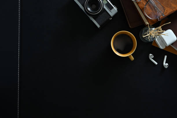 istock Stylish workplace with retro camera, coffee cup, earphones and glasses on black surface. Top view with copy space for your text. 1496059482