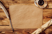 Old paper on brown wood background with feather