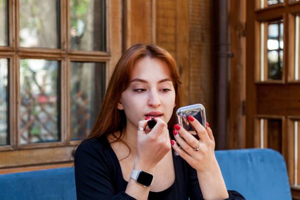 istock A girl in a cafe at a table paints her lips with red lipstick 1496065433