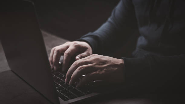 Hacker hand typing on laptop computer keyboard when trying to launch cyber attack to victim