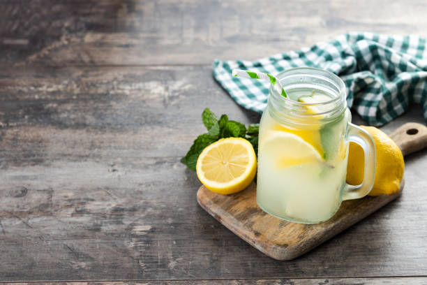 Bebida de limonada em um copo de frasco e ingredientes na mesa de madeira - foto de acervo