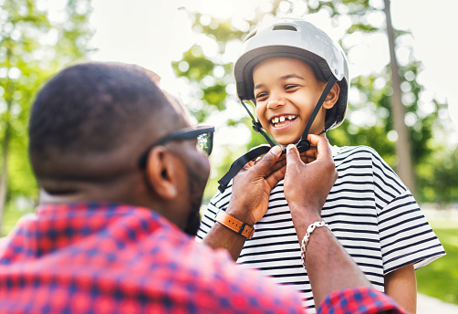 Happy family: father puts on  son helmet for safe cycling in park   in nature