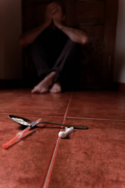 istock man lying on the floor in the dark with his hands on his head desolate from drugs 1496067636