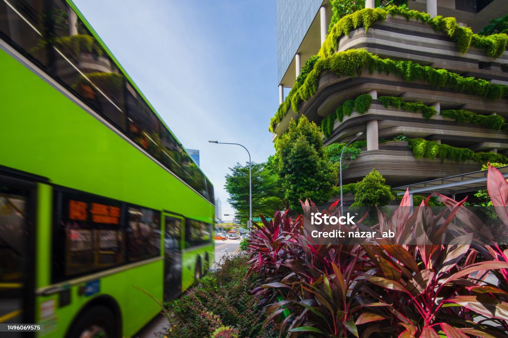 Electric bus passing along the Park Royal hotel eco building in Singapore. Electric bus in Pickering Street and eco building in central Singapore initiative from Singapore Govt to keep the Country clean and green. Sustainable Lifestyle Stock Photo