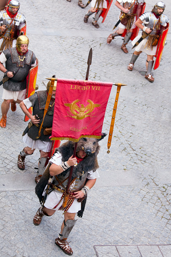 Lugo, Spain- June 11, 2022: Roman soldiers in an exhibition , traditional festival recreation , part of the parades of the Arde Lucus traditional festival, Roman Historical Reenactment.Metal suit of armor and helmet. Lugo city, Galicia, Spain. Banner and wild boar disguise.