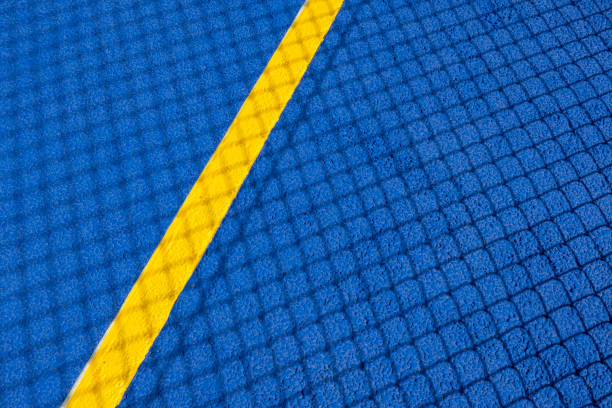 Sport field court background. Blue rubberized and granulated ground surface with yellow lines and tennis net shadow on ground. Top view Sport field court background. Blue rubberized and granulated ground surface with yellow lines and tennis net shadow on ground. Top view. rubberized stock pictures, royalty-free photos & images