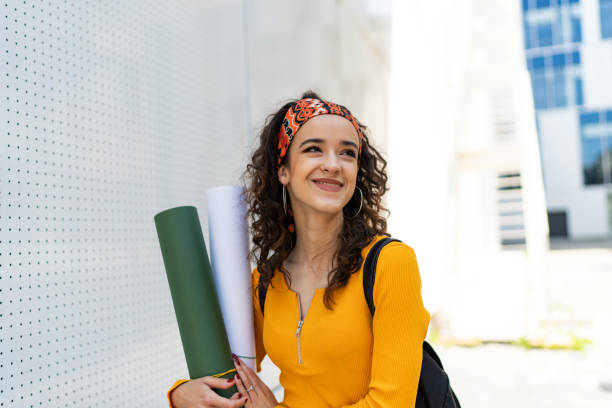 istock Smiling woman architect student holding paper drawing blueprints 1496081436