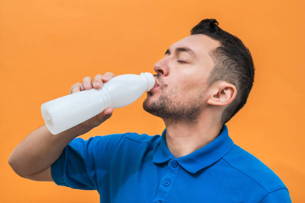 istock Handsome man drinks yogurt or milk on orange background. Mock up copy space 1496081483
