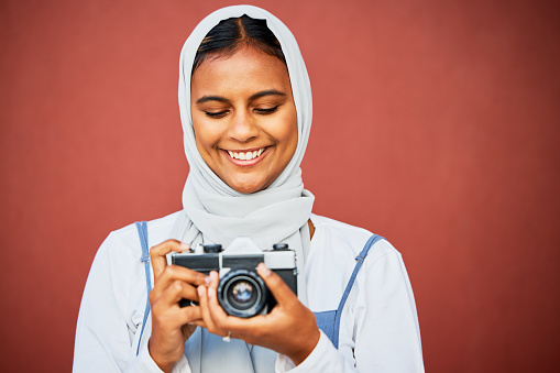 Photography, muslim woman holding camera and mockup, face with smile isolated on red background. Creative professional lifestyle photographer in hijab, hobby or career taking happy photo in studio.