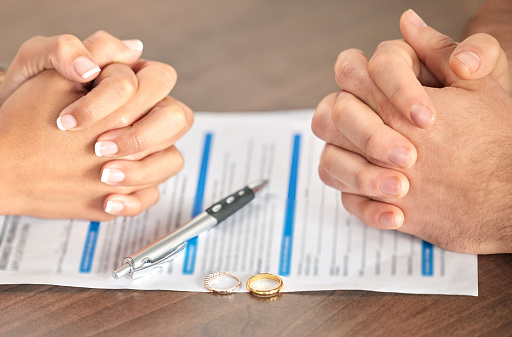 Divorce, signing and hands of a couple with a document for court, deal and legal paperwork. Together, conflict and married man and woman with an agreement, paperwork and form to end a marriage