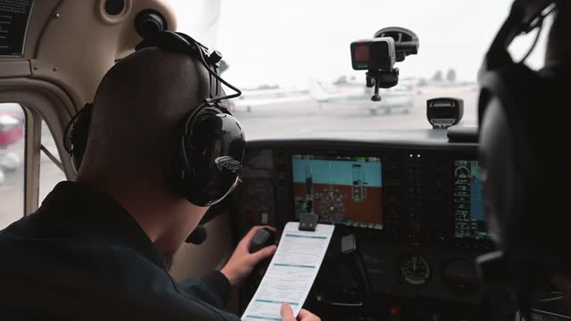 The student pilot is conducting the final pre-flight inspection with their instructor inside the cockpit