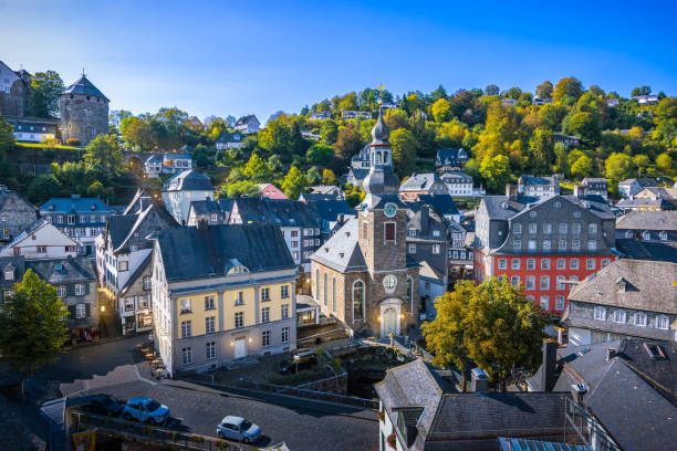 Aerial view of church and colorful buildings illuminated with lights in the old city center of Monschau, Eifel, Germany. Evening view. Travel image.