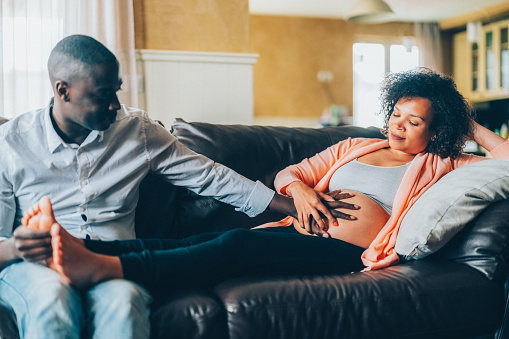 Pregnant woman on the couch enjoys a massage from her husband